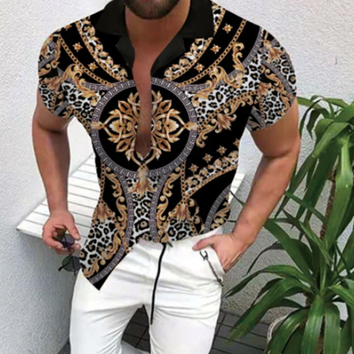 Stylish man wearing black and gold baroque print shirt with leopard details and white pants, holding sunglasses
