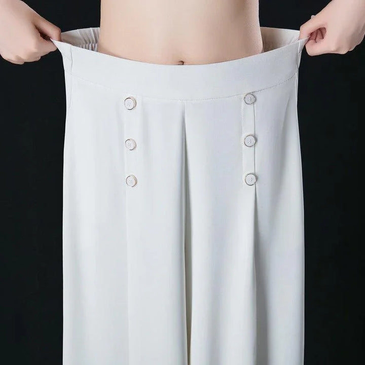 Person holding oversized white high-waisted pants with button details against black background