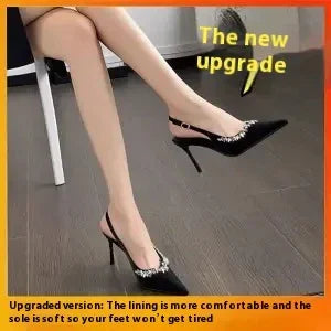 Black high heel slingback shoes with decorative gems worn by a seated woman on a gray floor