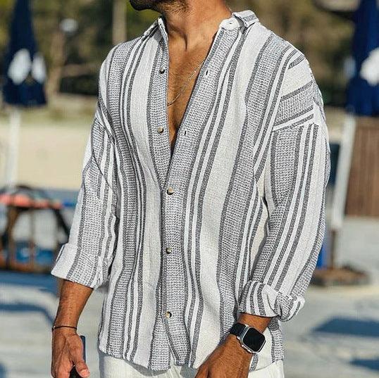 Man wearing casual white and gray striped button-up shirt with rolled sleeves outdoors
