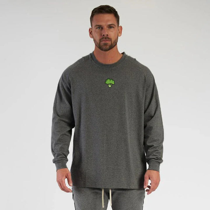 Man wearing dark gray long sleeve shirt with small green broccoli logo on chest