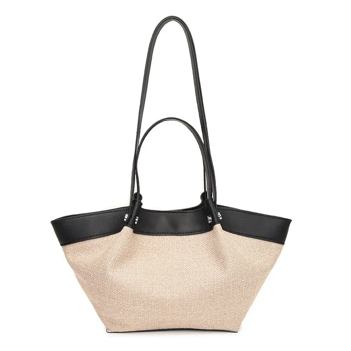 Beige canvas tote bag with black leather trim and dual handles on white background