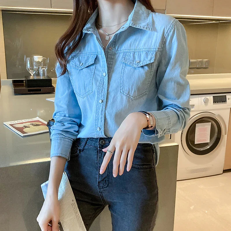 Woman in light blue denim shirt and high-waisted dark jeans in modern kitchen with washer
