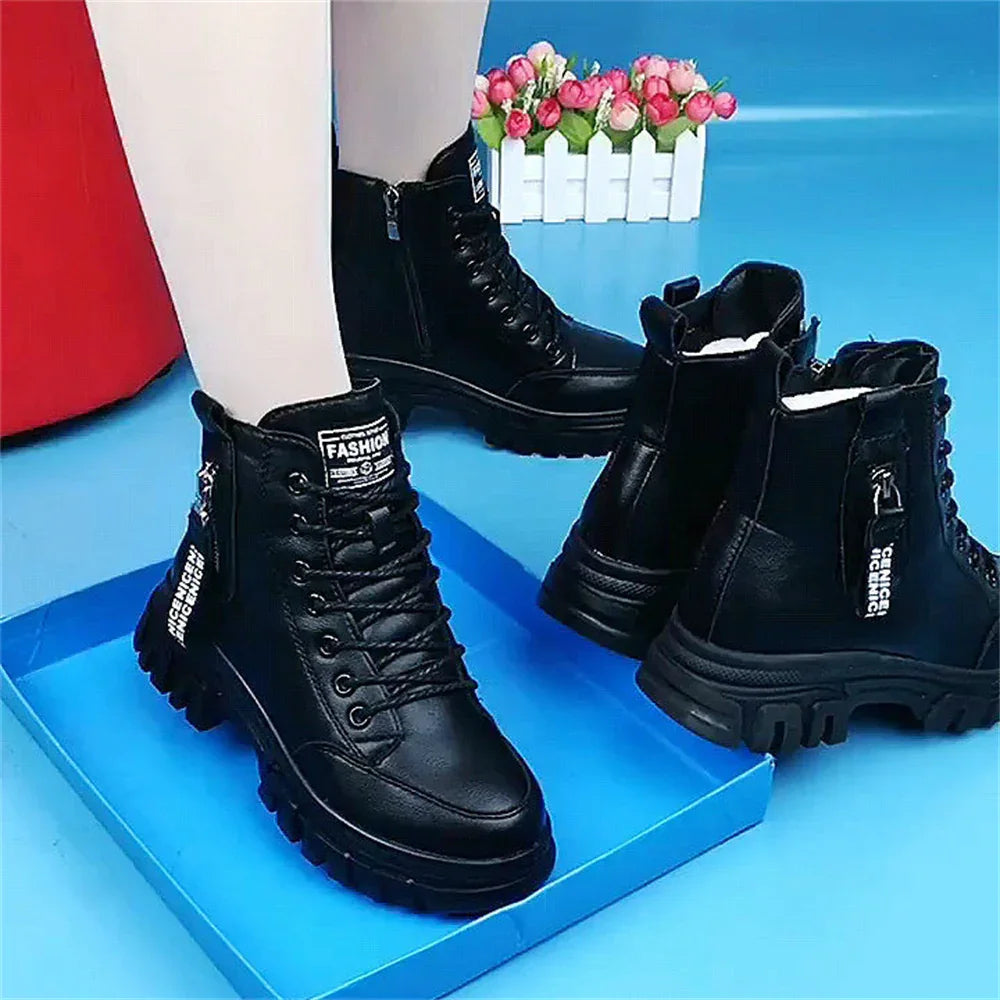 Black chunky combat boots with lace-up and zipper detail, worn on mannequin legs against blue background