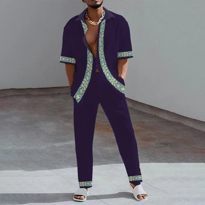 Man wearing dark navy casual set with patterned trim shirt and pants, standing on concrete floor.