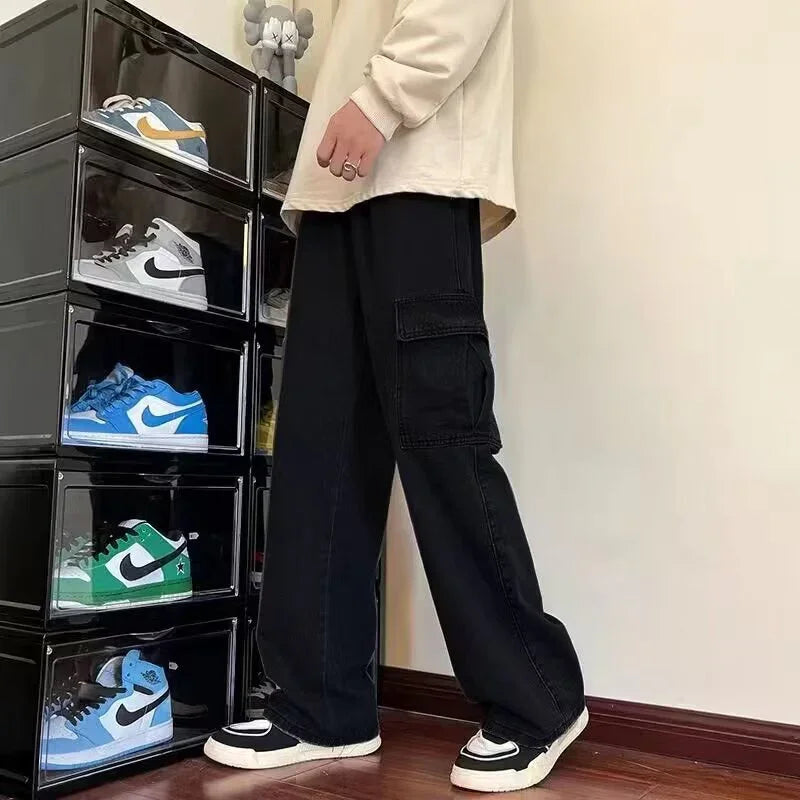 Person wearing black cargo pants and black white sneakers standing beside black sneaker storage boxes with colorful Nike shoes