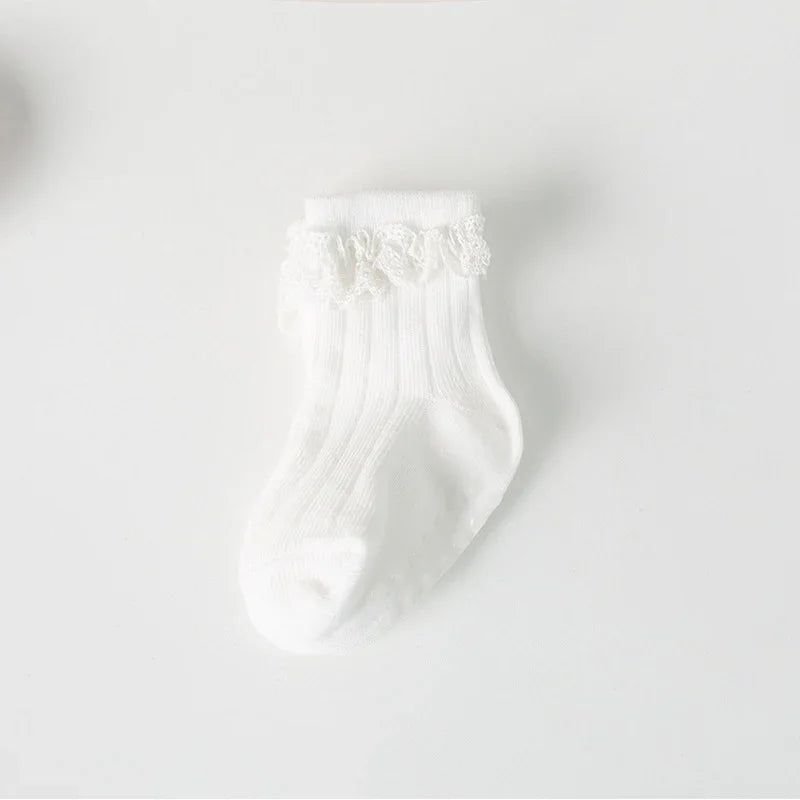White baby sock with ribbed texture and lace frill detail on plain background