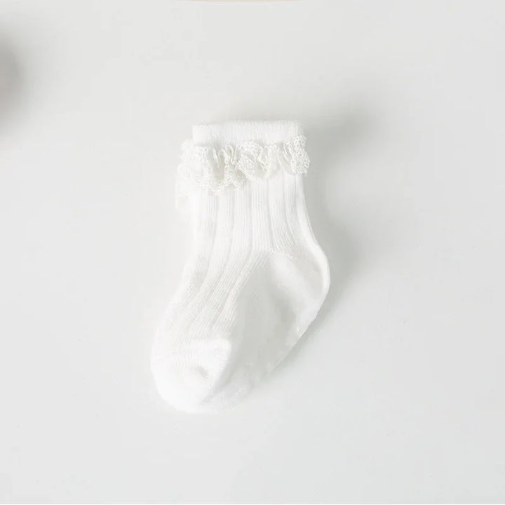 White baby sock with ribbed texture and lace frill detail on plain background