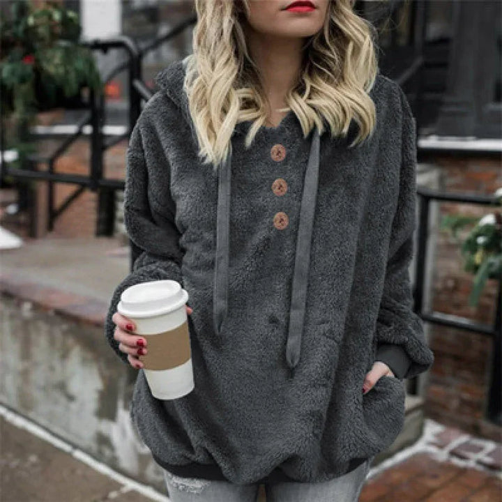 Woman wearing cozy dark gray fleece pullover with buttons holding takeaway coffee cup outdoors