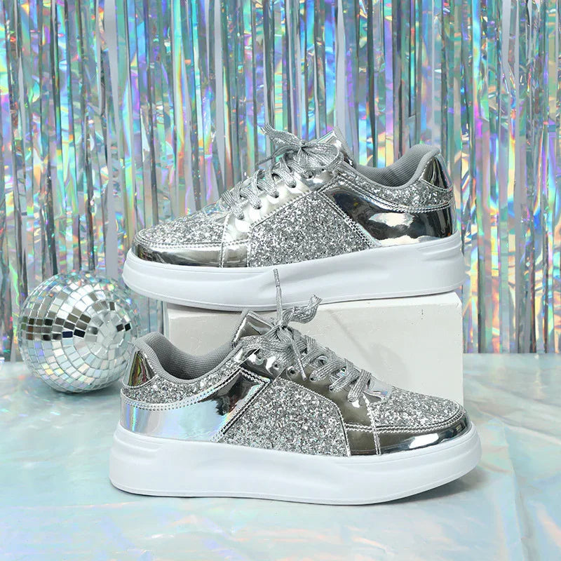 Silver glitter and metallic sneakers with white soles on white block, disco ball and holographic backdrop