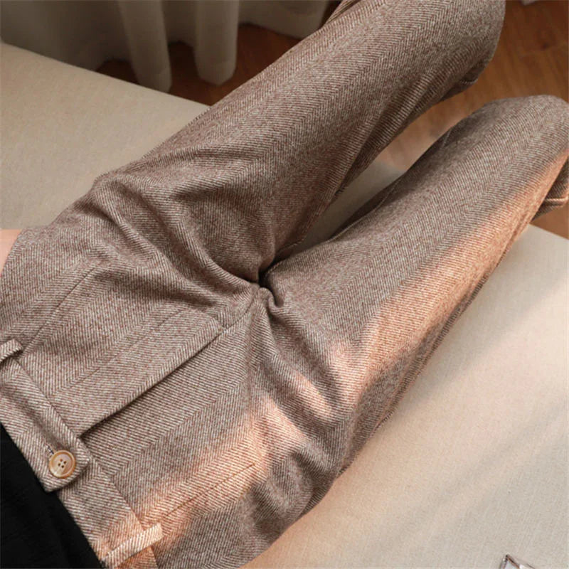 Close-up of brown herringbone wool trousers with button detail, worn while reclining on beige sofa
