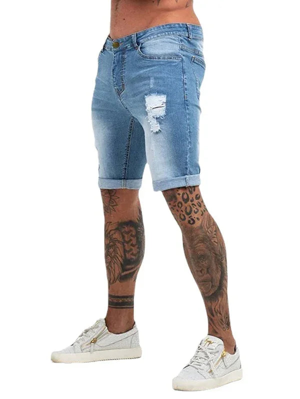 Man wearing light blue ripped denim shorts and white sneakers with tattooed legs