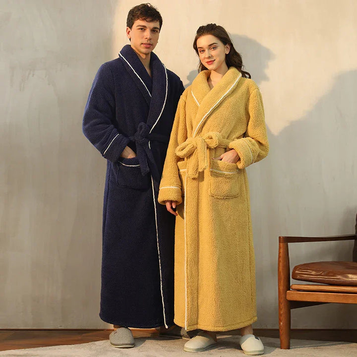 Man and woman wearing cozy long fleece bathrobes in navy blue and yellow with pockets, standing indoors