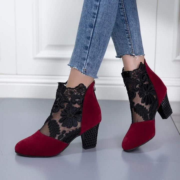 Women's red suede ankle boots with black floral lace overlay and block heels, worn with frayed hem jeans