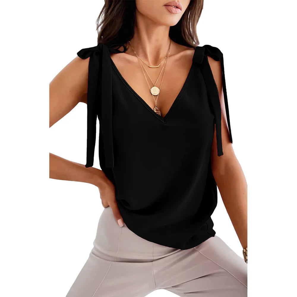 Woman wearing black sleeveless V-neck top with tie shoulder straps and beige pants
