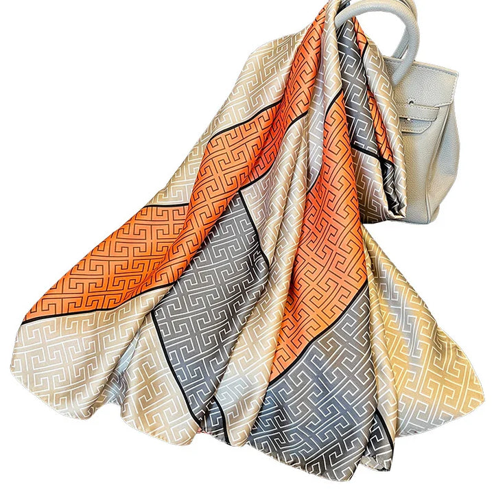 Elegant silk scarf with geometric pattern in orange, beige, and gray draped over a white leather handbag