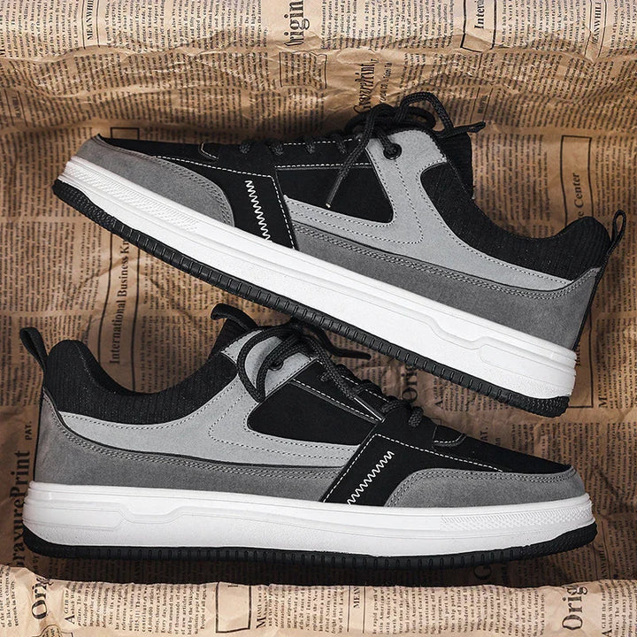 Pair of black and gray casual sneakers with white soles on newspaper background