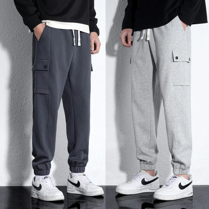 Men's casual cargo jogger pants in dark gray and light gray paired with white Nike sneakers.