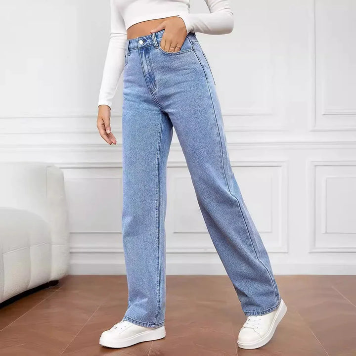 Woman wearing light blue high-waisted straight jeans with white sneakers in a modern indoor setting