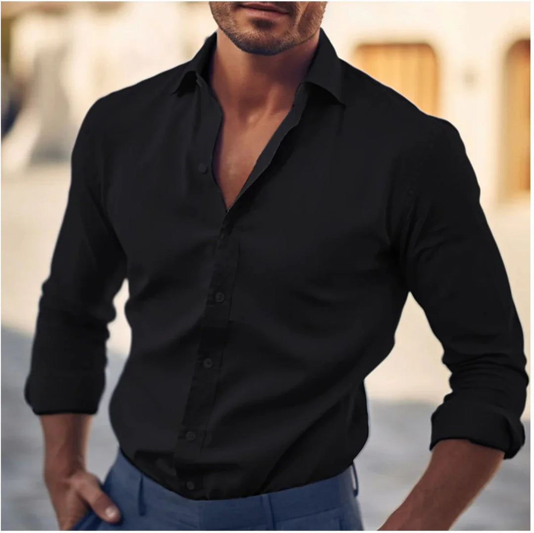Man wearing a stylish black long sleeve button-up shirt with rolled cuffs and blue pants