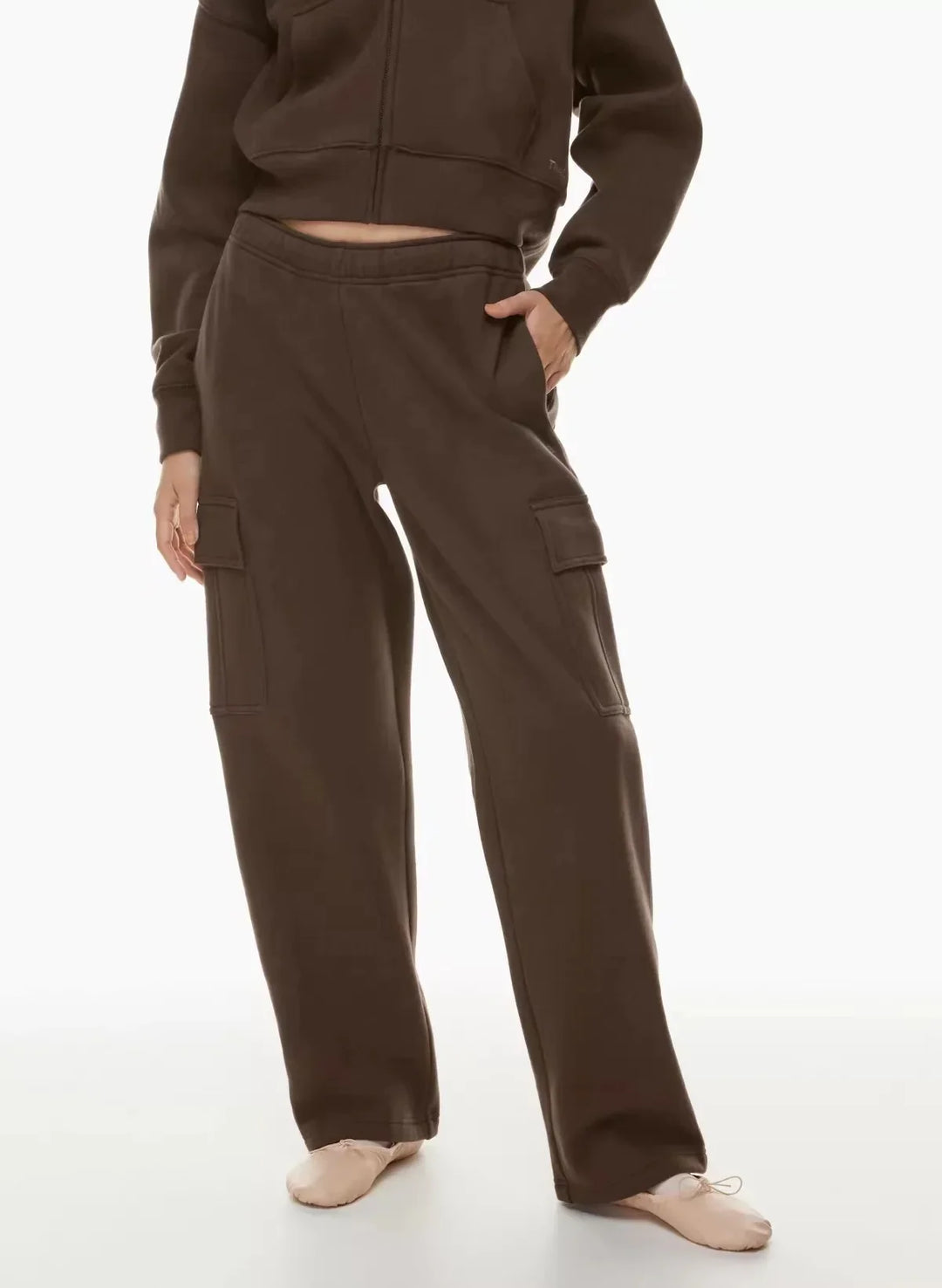 Woman wearing brown cargo sweatpants and cropped zip-up hoodie on white background