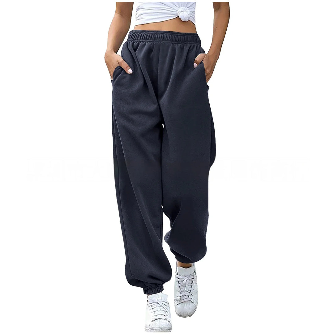 Woman wearing black elastic waist relaxed jogger pants and white sneakers on white background