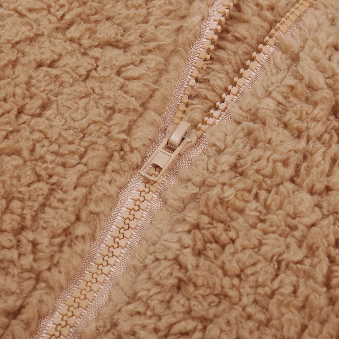 Close-up of beige teddy fleece fabric with matching plastic zipper