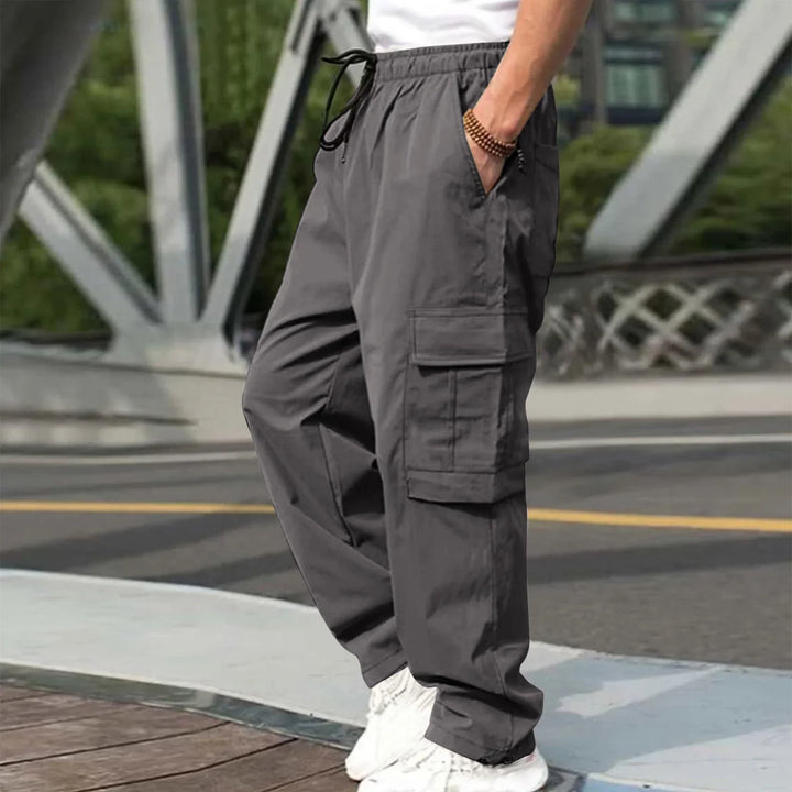 Man wearing gray cargo pants with drawstring waist and white sneakers outdoors
