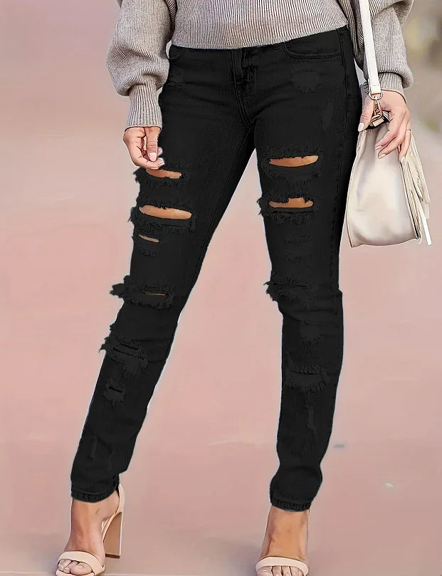 Woman wearing black ripped skinny jeans with beige heeled sandals and carrying a white handbag