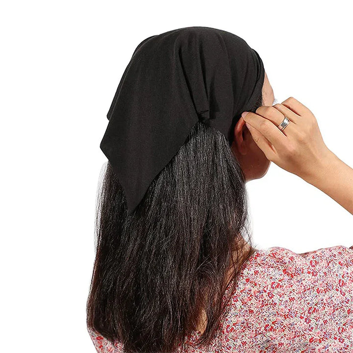 woman with long dark hair wearing a black headscarf and floral top adjusting hair