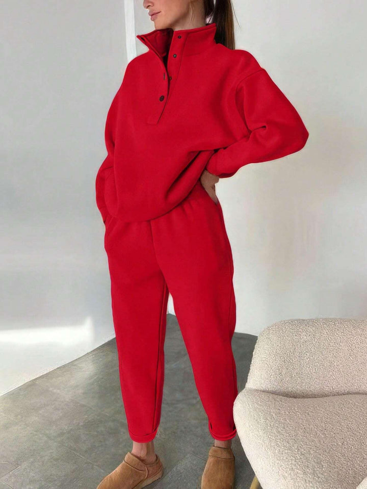 Woman wearing bright red cozy sweatshirt and joggers with brown slippers in modern minimal living room