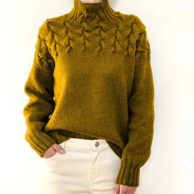 Mustard yellow knitted sweater with cable pattern on yoke, worn with white pants