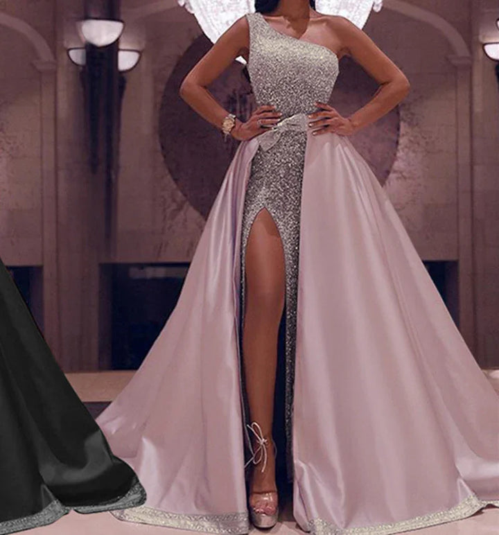 Elegant woman wearing a one-shoulder silver sequin gown with a high slit and pink satin overskirt