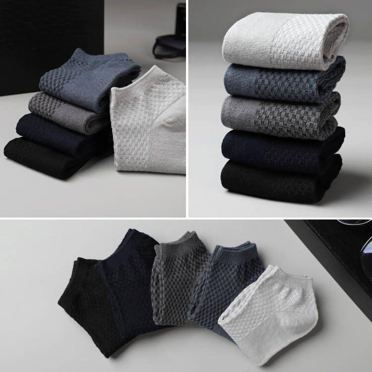 Stacked and spread men's ankle socks in black, navy, gray, and white with waffle knit pattern on gray surface