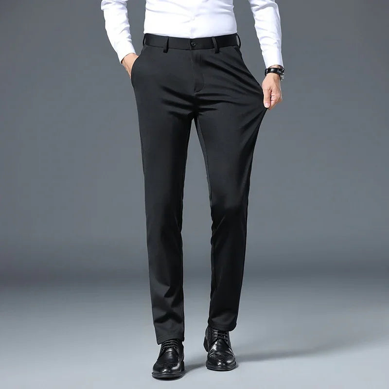Man wearing slim fit black dress pants with black belt and black shoes against gray background