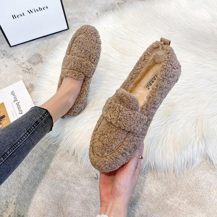 Plush brown fleece slippers worn and held over white faux fur rug, cozy indoor footwear for women