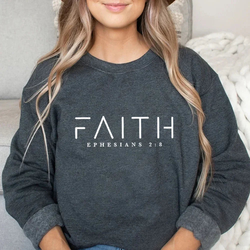 Woman wearing dark gray sweatshirt with FAITH and Ephesians 2:8 text on front