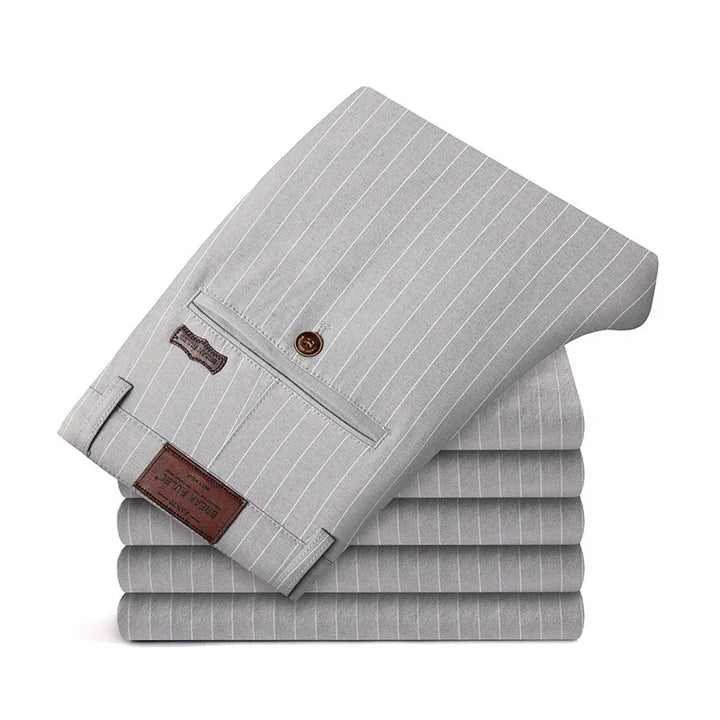 Stack of neatly folded gray pinstripe dress pants with button pocket and leather label