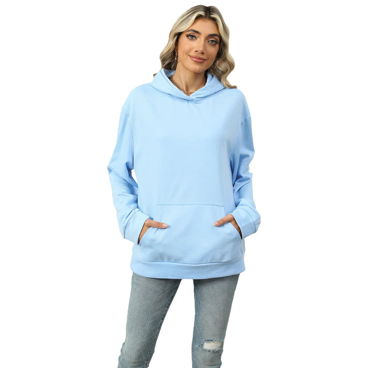 Woman wearing light blue oversized hoodie with front pocket and ripped gray jeans