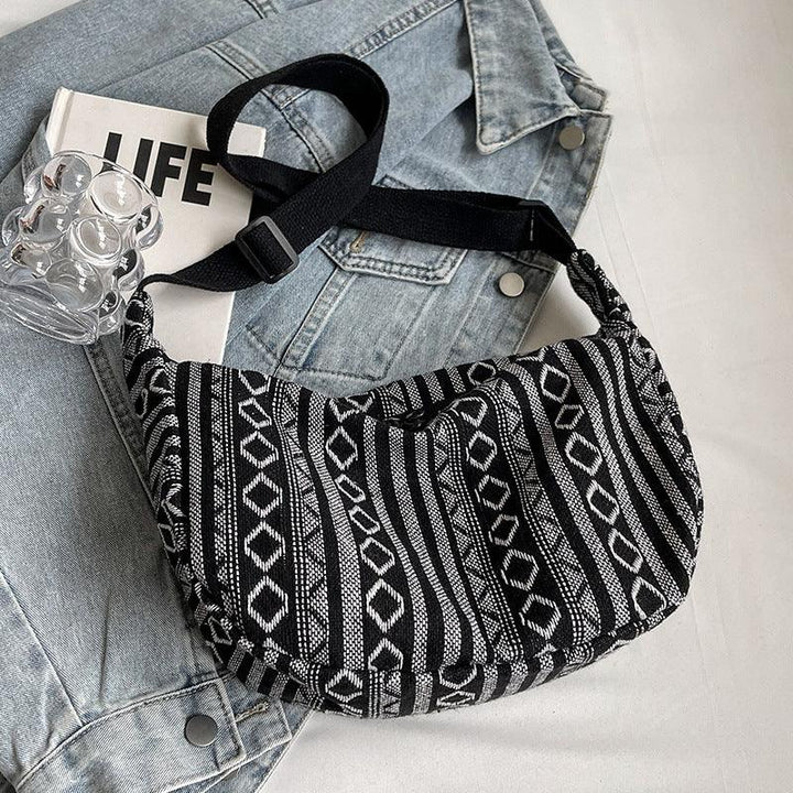 Black and white woven patterned shoulder bag on light blue denim jacket with LIFE magazine and glass vase