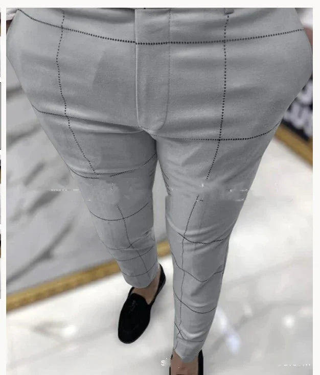 Close-up of men's slim fit gray checkered dress pants paired with black loafers on white floor