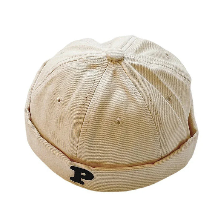 Beige cotton docker cap with black letter P embroidered on rolled brim