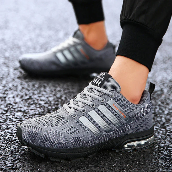 Close-up of gray athletic running shoes with breathable mesh and air-cushioned sole on asphalt