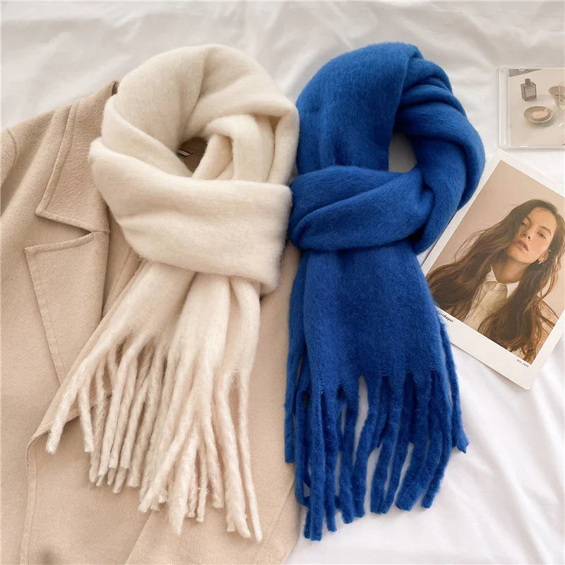 Soft beige and blue wool scarves with fringes displayed on a beige coat and white background