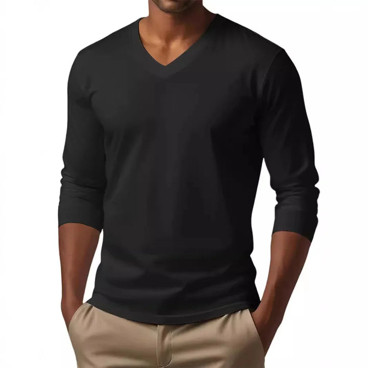 Man wearing black V-neck long sleeve shirt with beige pants and hands in pockets