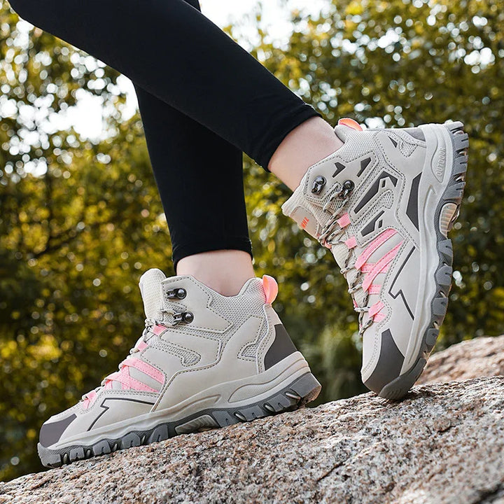 Light gray hiking boots with pink accents worn with black leggings on rocky terrain outdoors
