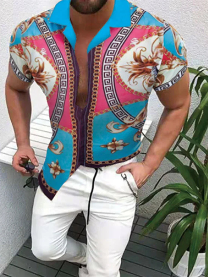 Man wearing vibrant short-sleeve shirt with blue, pink, and gold baroque pattern paired with white pants