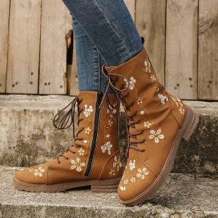 Brown leather lace-up ankle boots with floral embroidery worn with blue jeans on stone steps