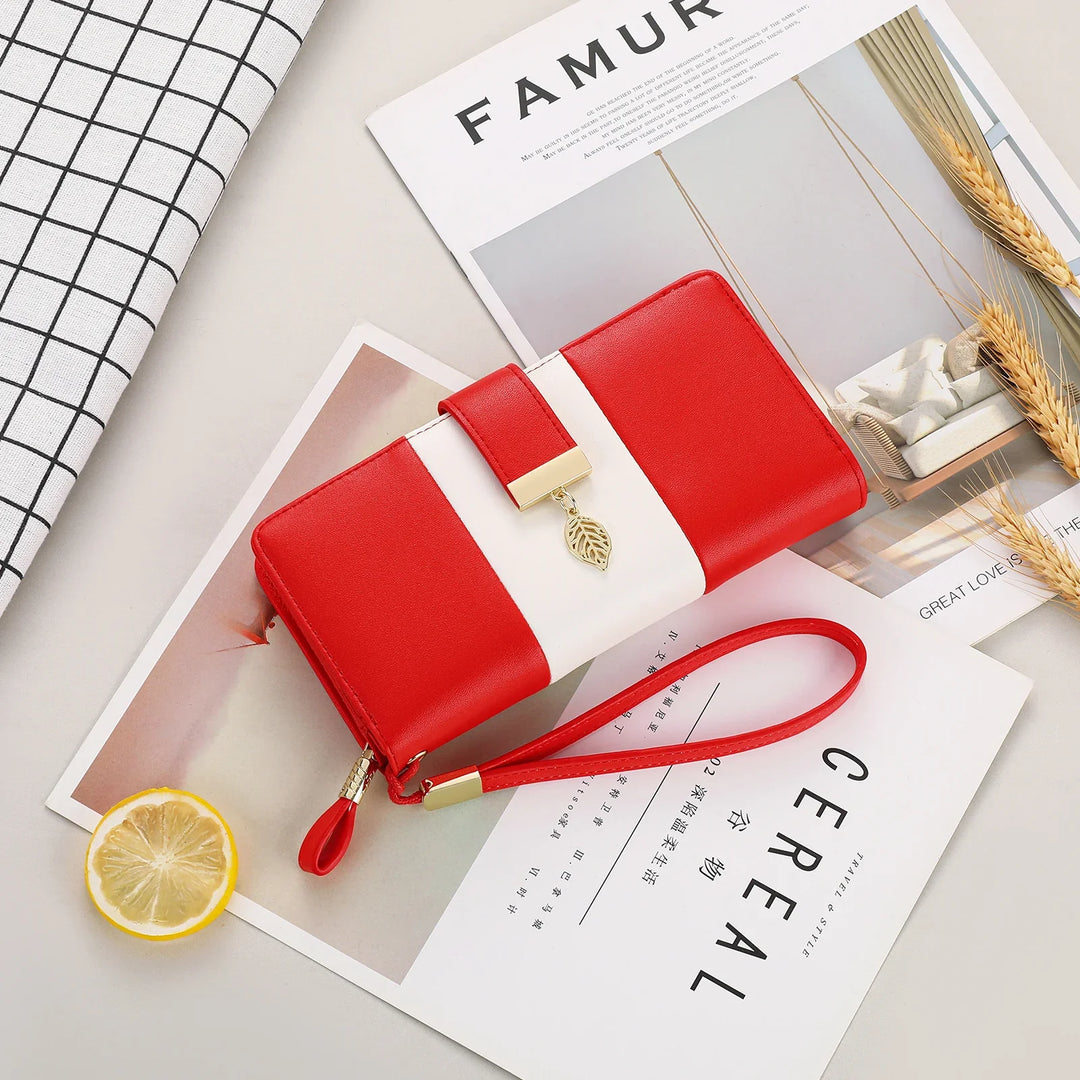 Red and white wristlet wallet with gold leaf charm on lifestyle magazine pages with wheat and lemon slice