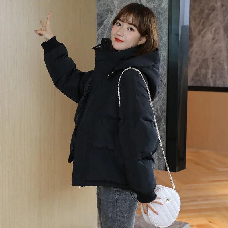 Young woman wearing black padded jacket and gray jeans, carrying white round quilted handbag indoors